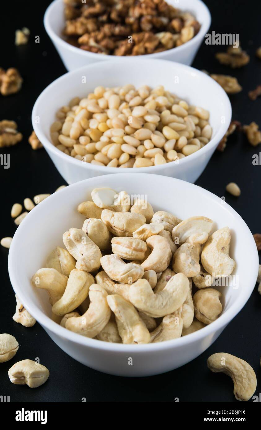 superfood concept, cedar, walnuts, cashew nuts in a plate on a black background Stock Photo