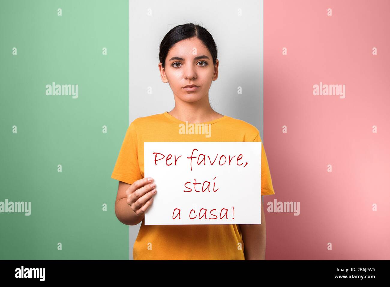 coronavirus advice to stay at home. woman holding a placard against italian flag asking people not to leave their houses Stock Photo
