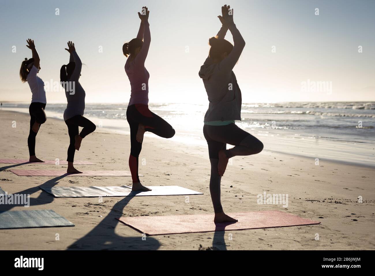 Side view of women doing yoga together at the beach Stock Photo