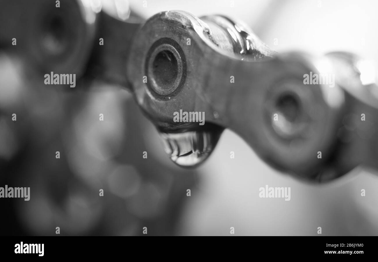 Closeup of bicycle chain with droplet of lubricant and cassette cog
