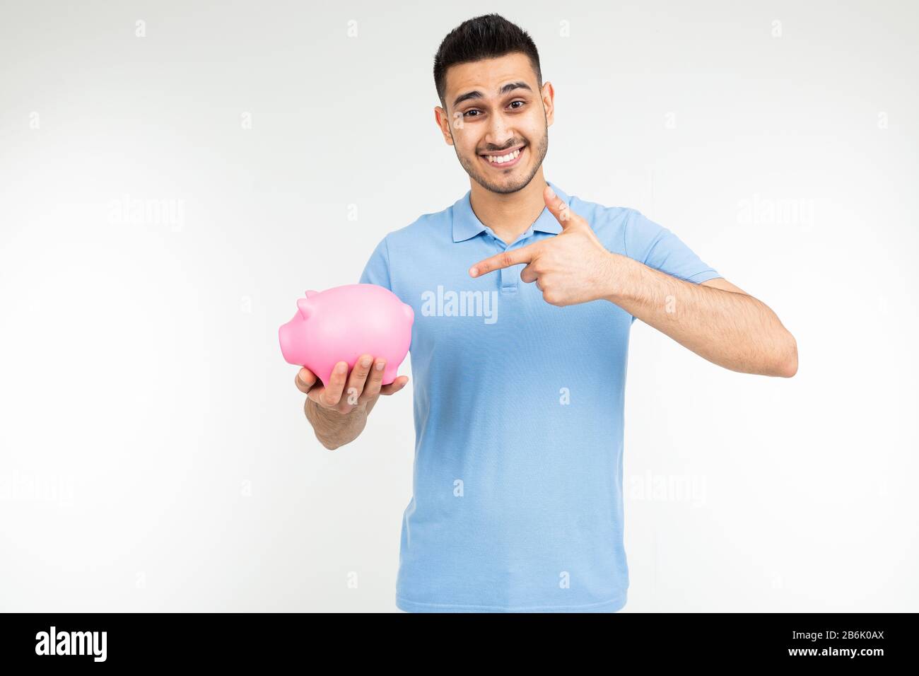 brutal man in a blue shirt holds a piggy bank and points a finger at it ...