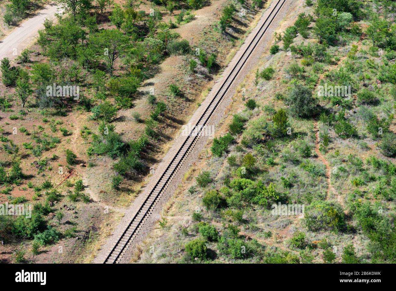 Aerial view of railway track surrounded by green vegetation and dry soil in Victoria Falls, Zimbabwe in Africa. Stock Photo