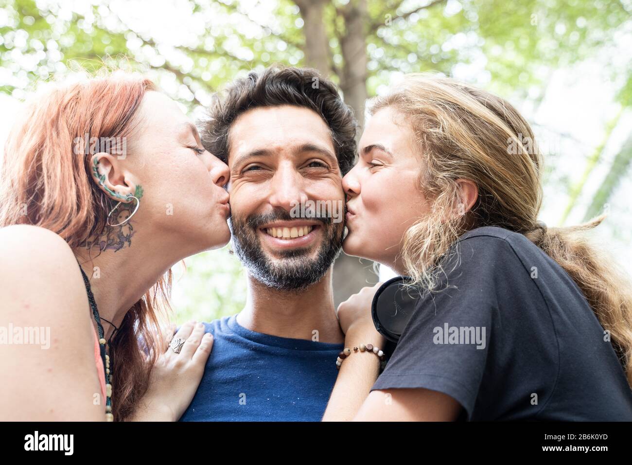 two girls kissing a happy boy Stock Photo