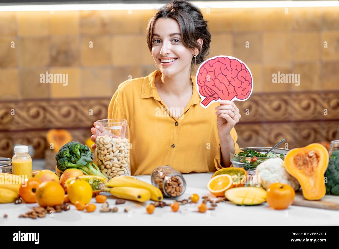 Woman holding human brain model with variety of healthy fresh food on the table. Concept of balanced nutrition for brain health Stock Photo