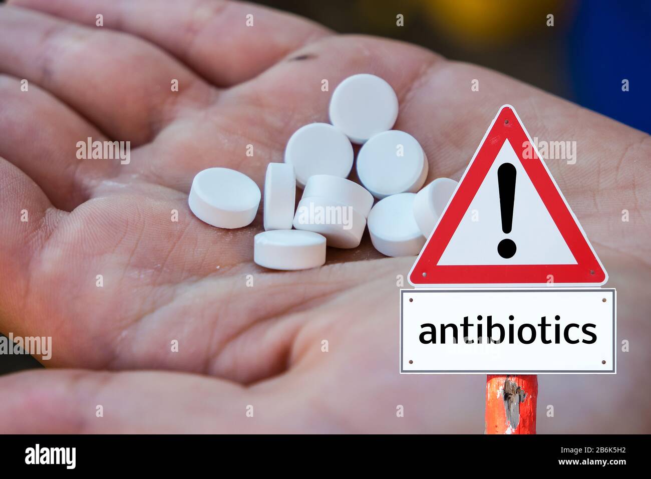 Hand holding tablets and warning sign of antibiotics Stock Photo