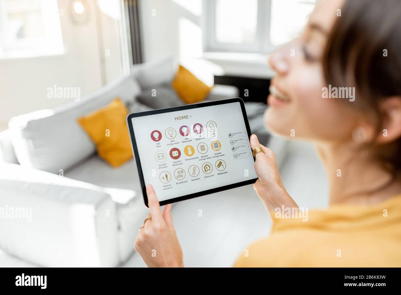 Happy woman controlling smart home devices using a digital tablet with ...