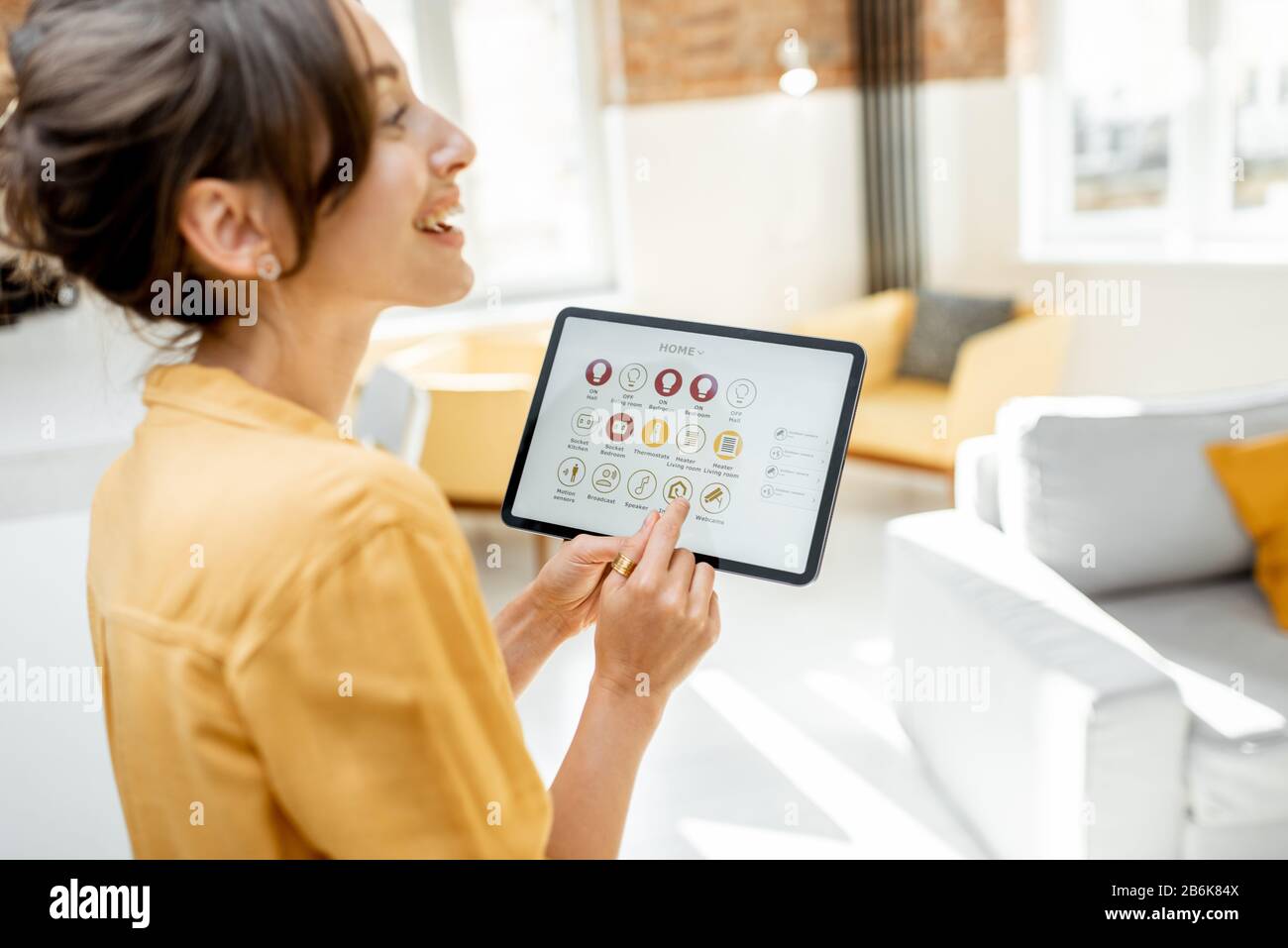 Happy woman controlling smart home devices using a digital tablet with ...