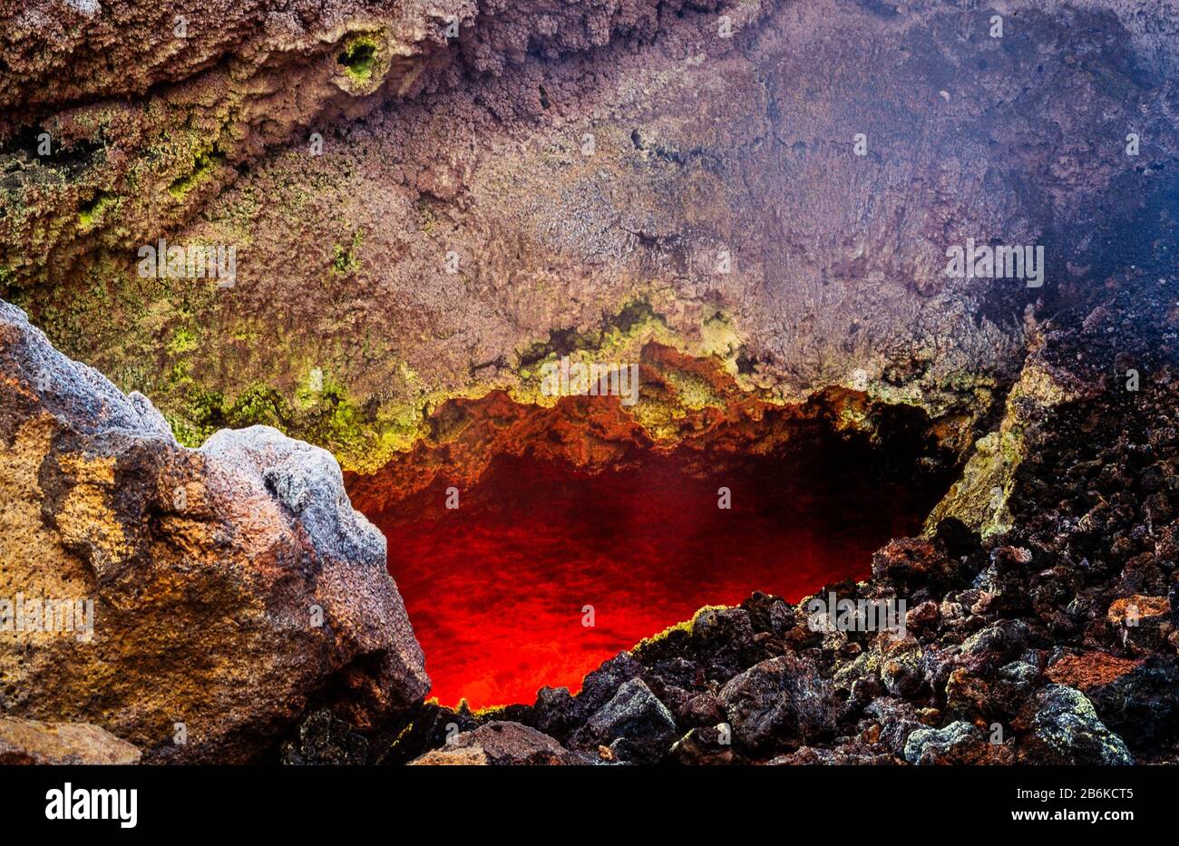 Looking into an active basalt lava flow from the solidified carapace, with  red, incandescent, high temperature, liquid lava flowing beneath Stock Photo