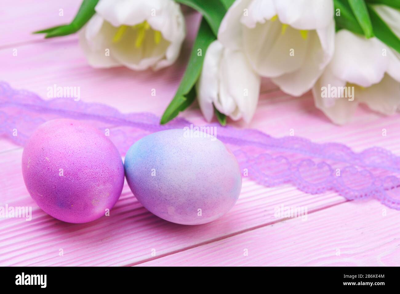 Easter background with colorful eggs and tulips over pink wood. Top ...