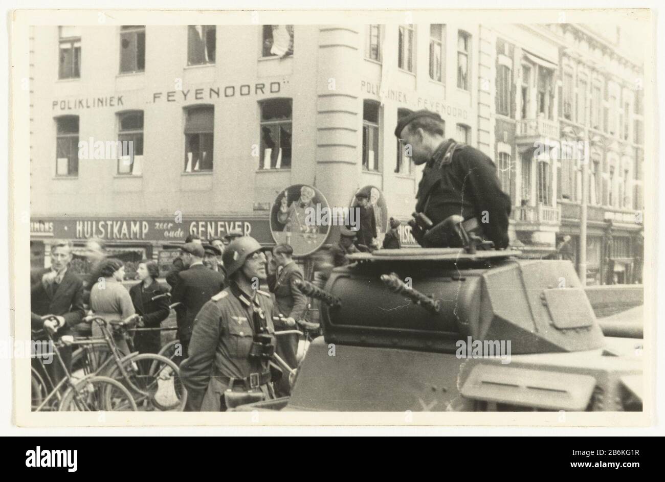 German army in Rotterdam German Wehrmacht soldiers in a tank with a cap and binoculars, talking to each other on the street in Rotterdam South. Whoever links a helmet, wearing glasses and a pair of binoculars around his neck. In the background you can see the Feyenoord Clinic. Dutch right stand, cycling, talking. It was going to make that contact German tanks of the 9th Armored Division with the men of the 3rd Battalion. The picture is Where: apparently made around the capitulation of the Netherlands on May 15 1940. Manufacturer : Photographer: anonymous place manufacture: Rotterdam Date: May Stock Photo