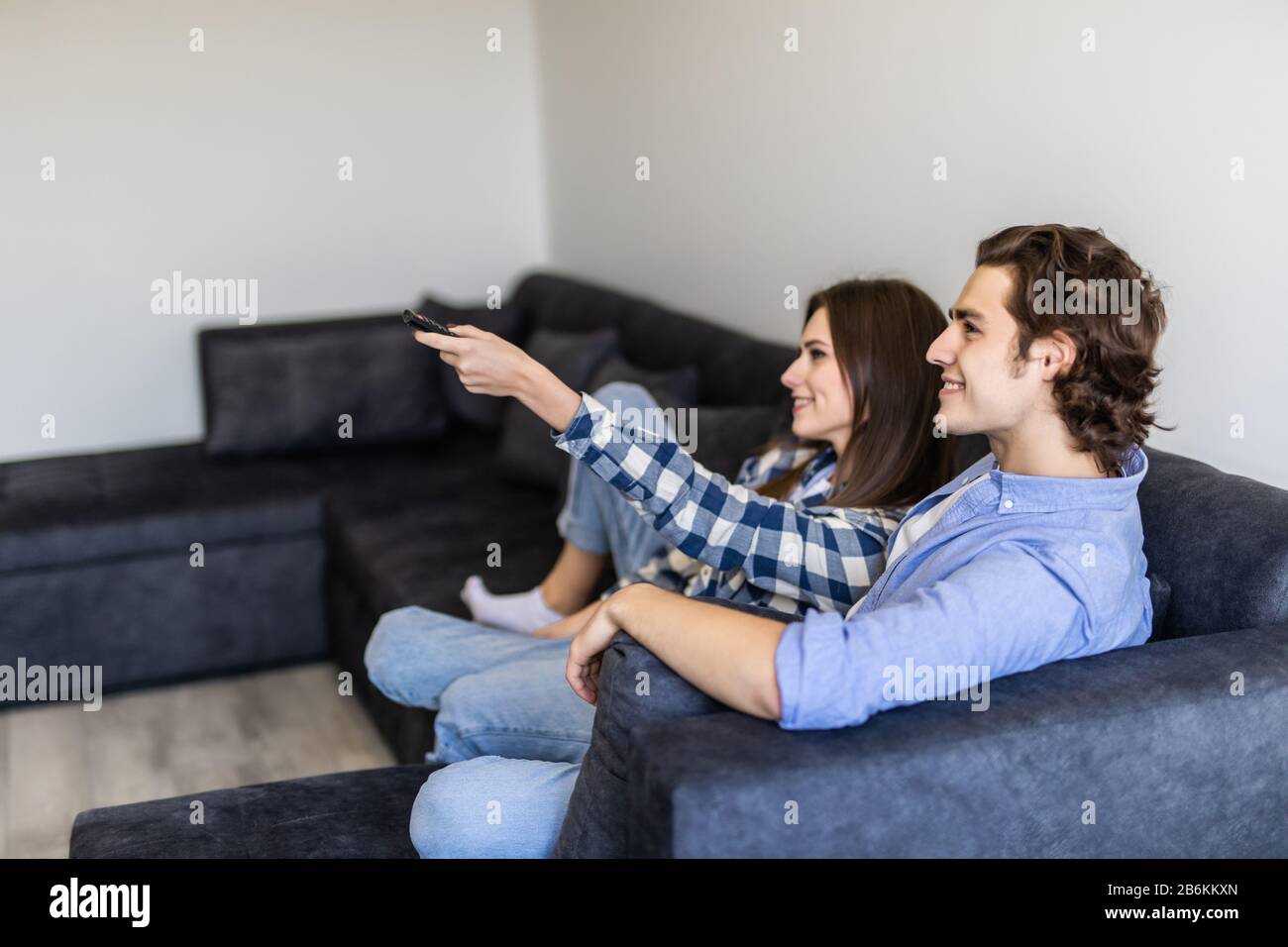 Portrait of couple cuddling while watching TV in their living room