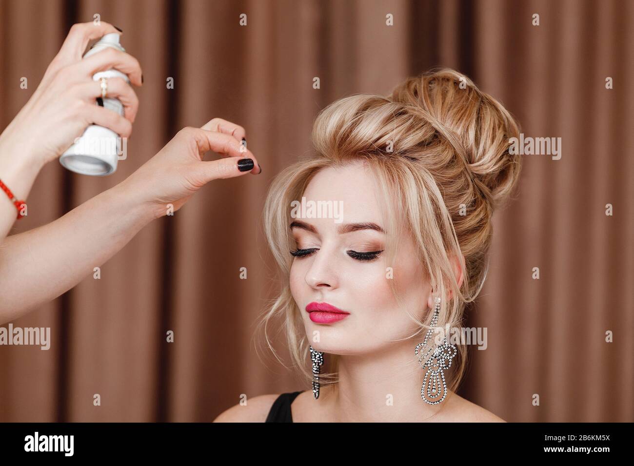 Professional Hairdresser using hair spray on client business woman hair at beauty salon Stock