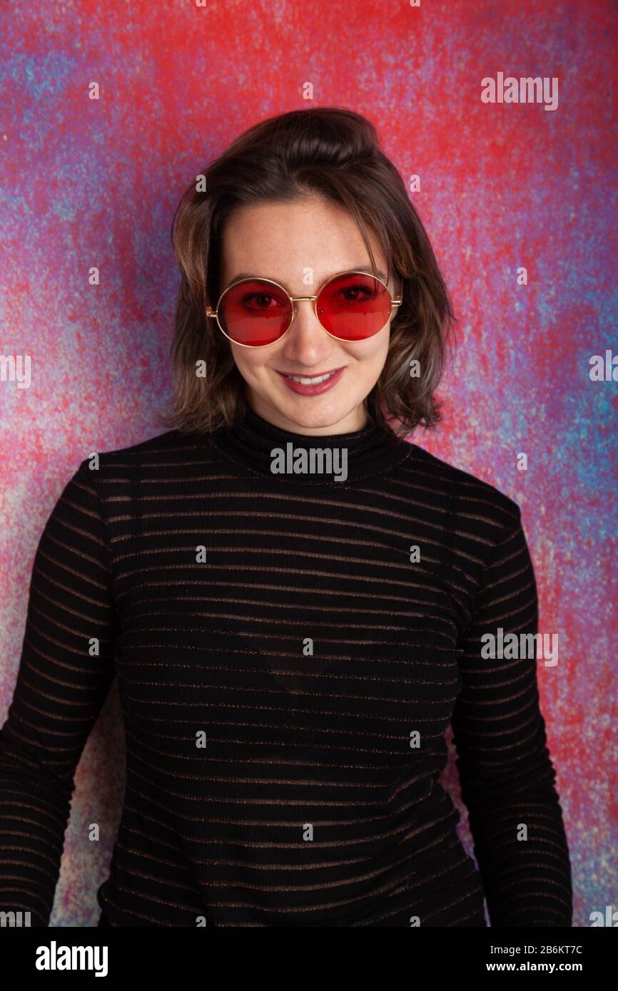 Portrait of a twenty year old woman wearing red spectacles and a see through top Stock Photo