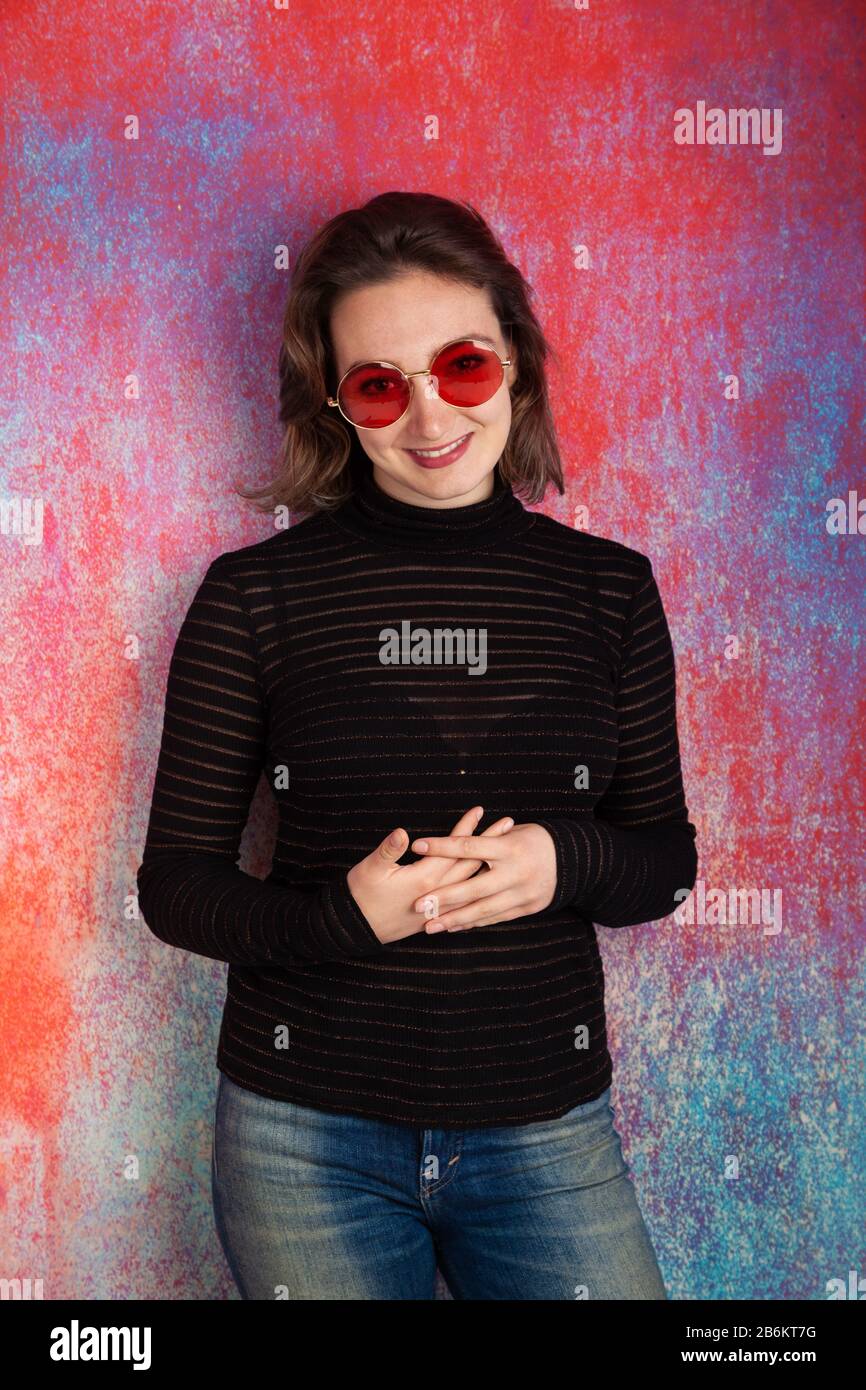 Portrait of a twenty year old woman wearing red spectacles and a see through top Stock Photo