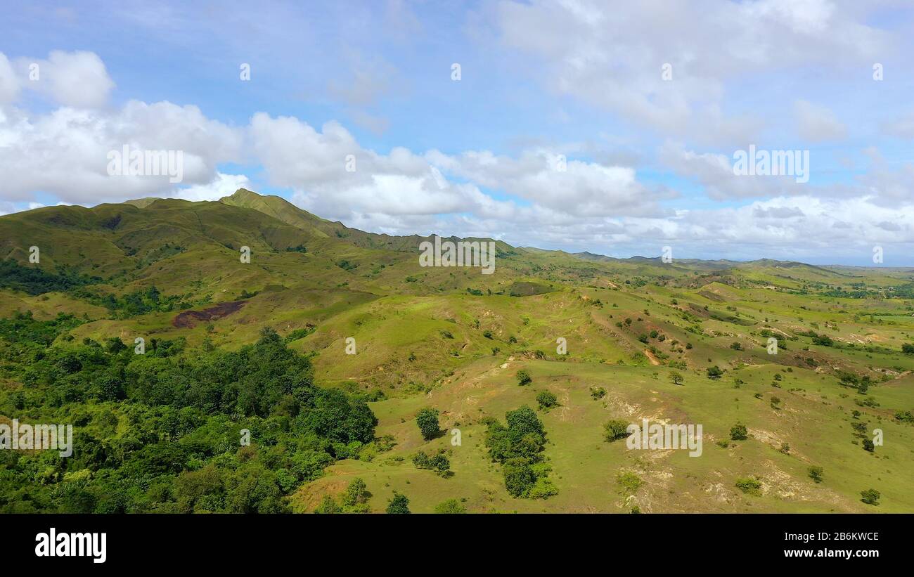 Green hills and blue sky with clouds. Beautiful landscape on the island of Luzon, aerial view. Mountain landscape in sunny weather. Stock Photo