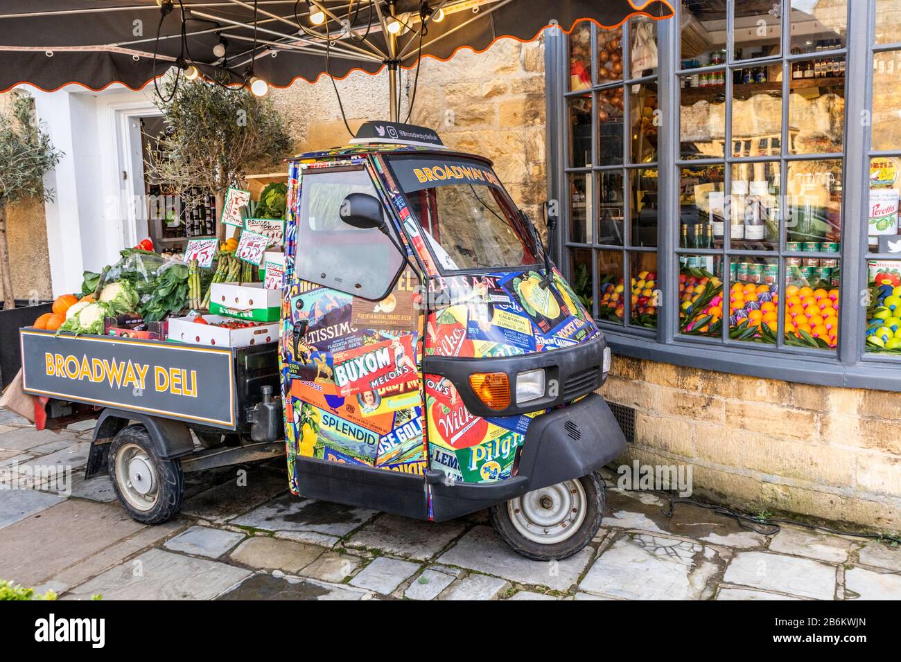 An Italian Piaggio Ape used to display fruit and vegetables outside the Broadway Deli in the Cotswold village of Broadway, Worcestershire UK Stock Photo