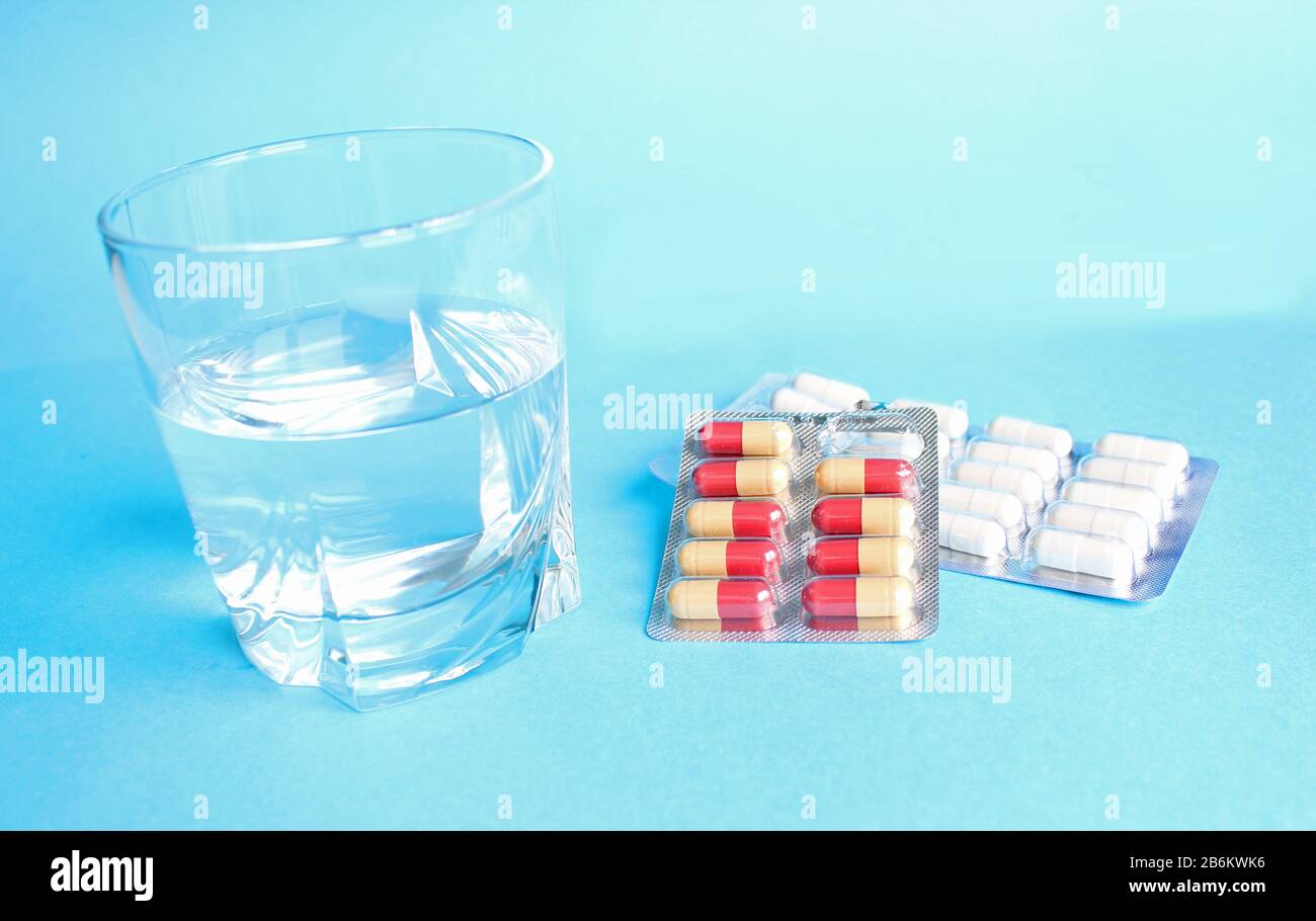 Glass of water and pills isolated on blue background Stock Photo