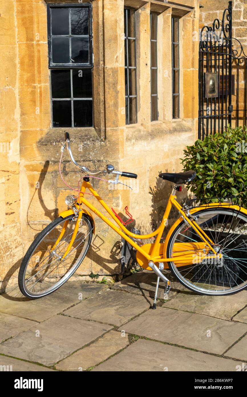 A yellow Veuve Clicquot bicycle outside the mellow yellow stone of the Lygon Arms Hotel in the Cotswold village of Broadway, Worcestershire UK Stock Photo