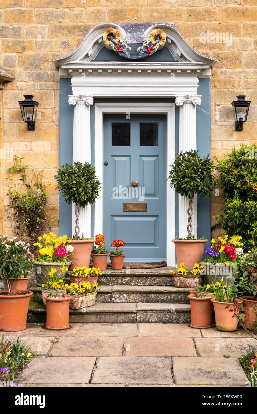 A display of spring flowers in pots outside a stone house in the Cotswold village of Broadway, Worcestershire UK Stock Photo