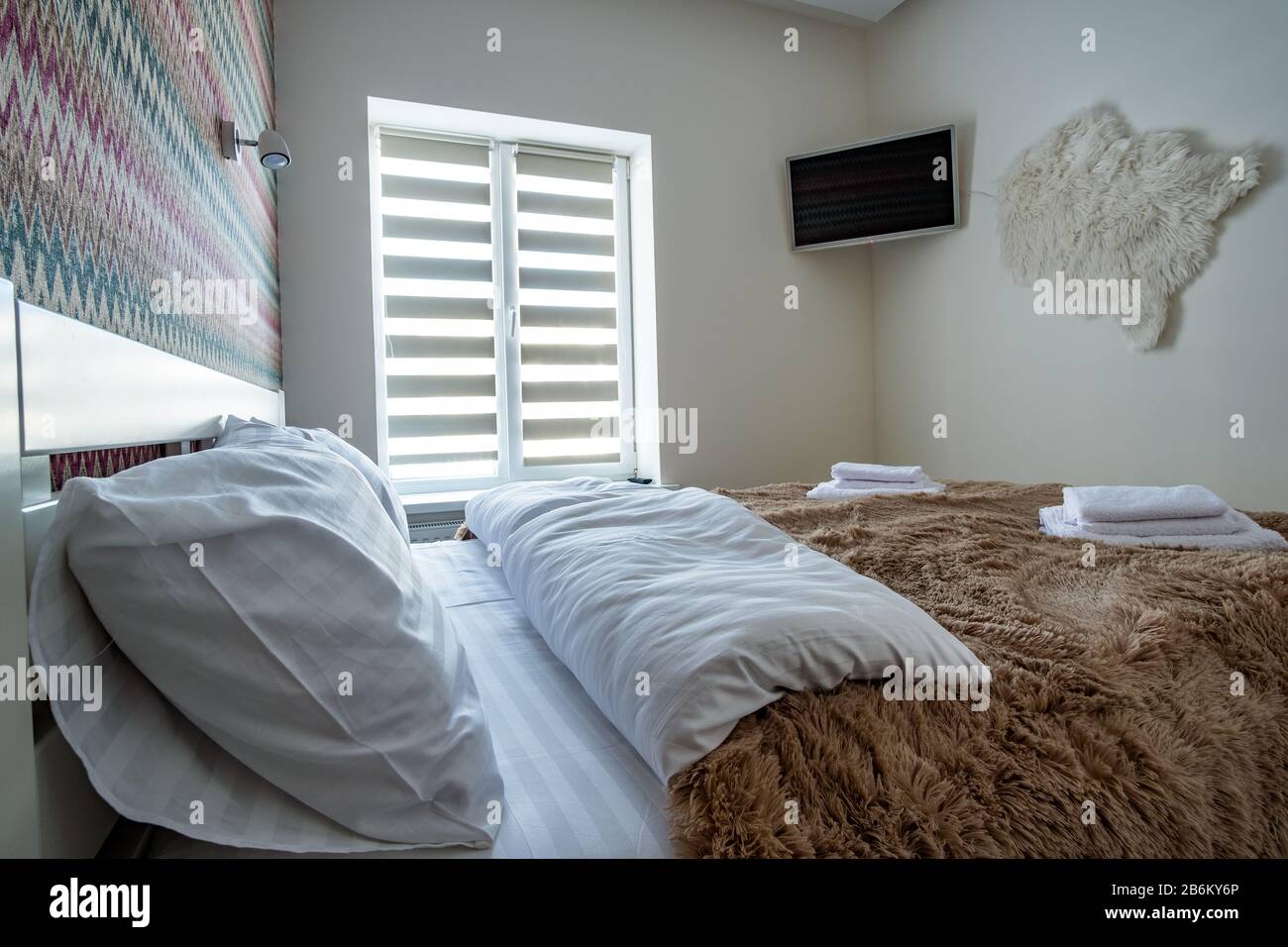 Interior of a spacious hotel bedroom with fresh linen on a big double