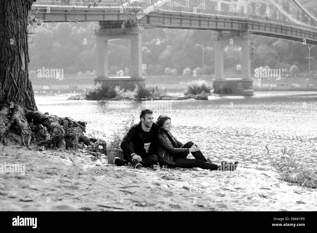 beautiful amazing funny cheerful young couple (man and woman) outdoor by the river on bridge background. Family, love and friendship concept Stock Photo
