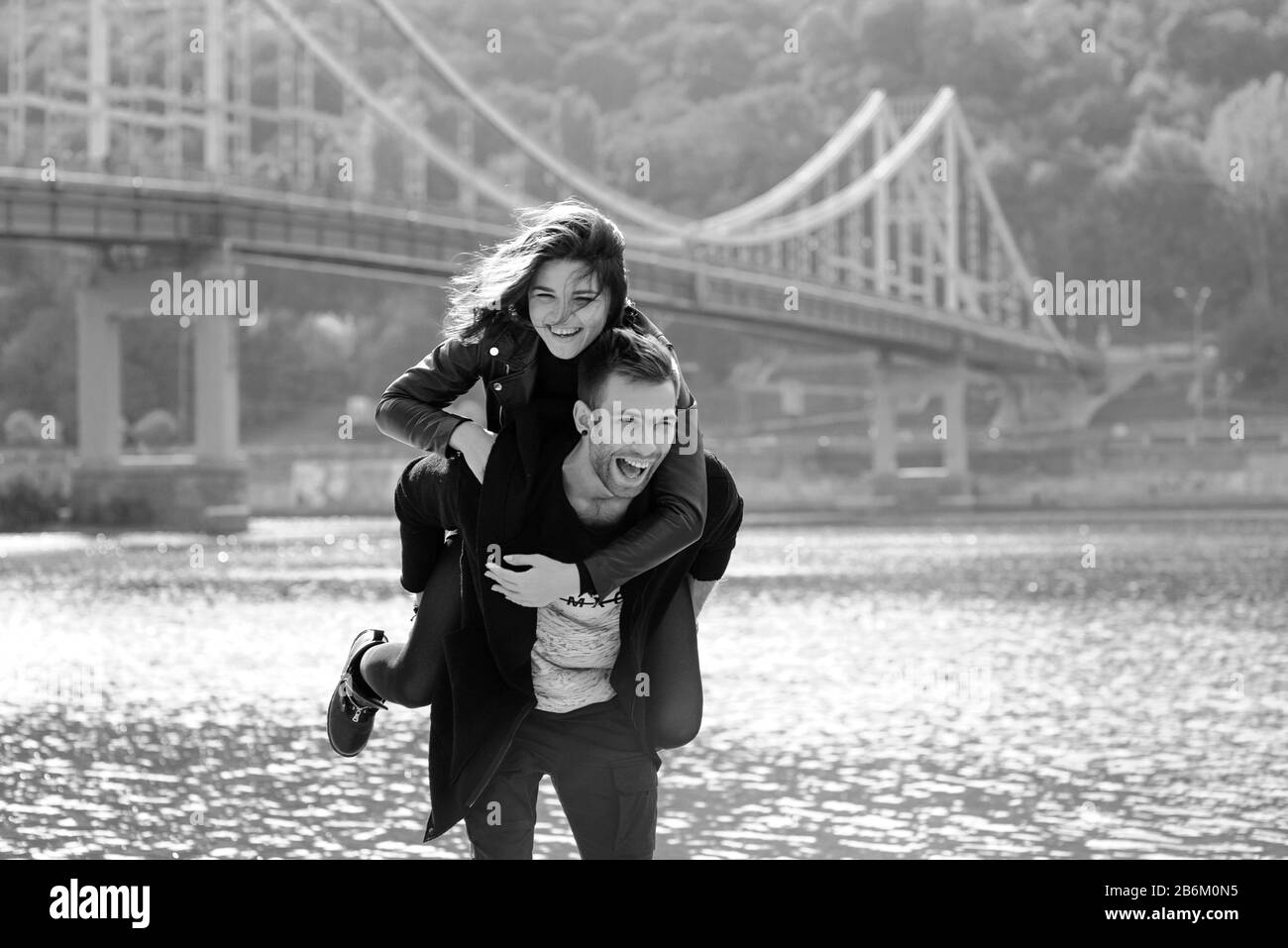 beautiful amazing funny cheerful young couple (man and woman) outdoor by the river on bridge background. Family, love and friendship concept Stock Photo