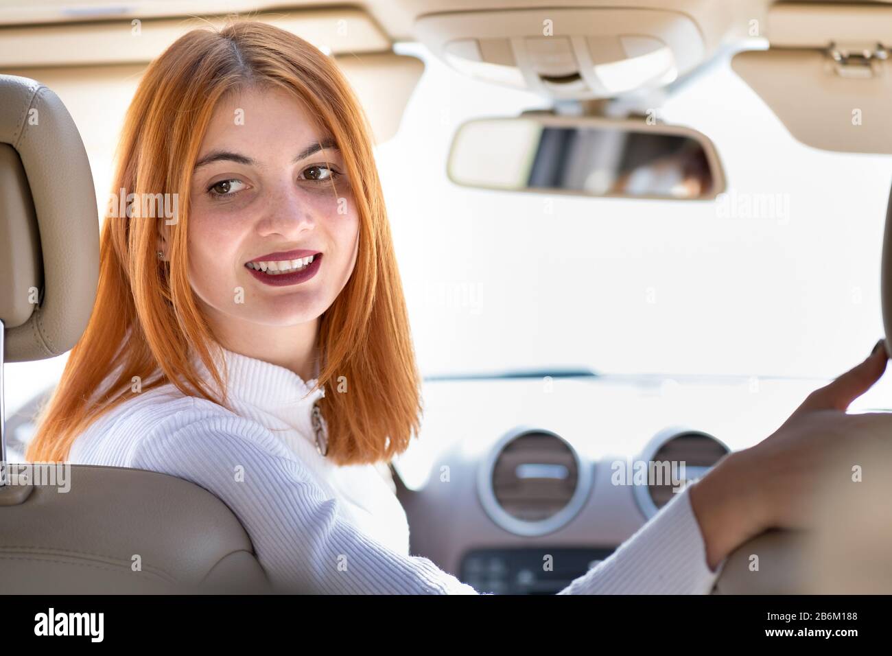Young redhead woman driver driving a car smiling happily Stock Photo
