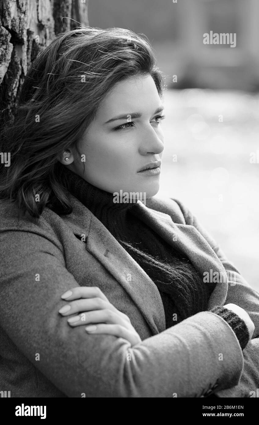 young beautiful brunette depressed sad woman by the river in the city on bridge background Stock Photo