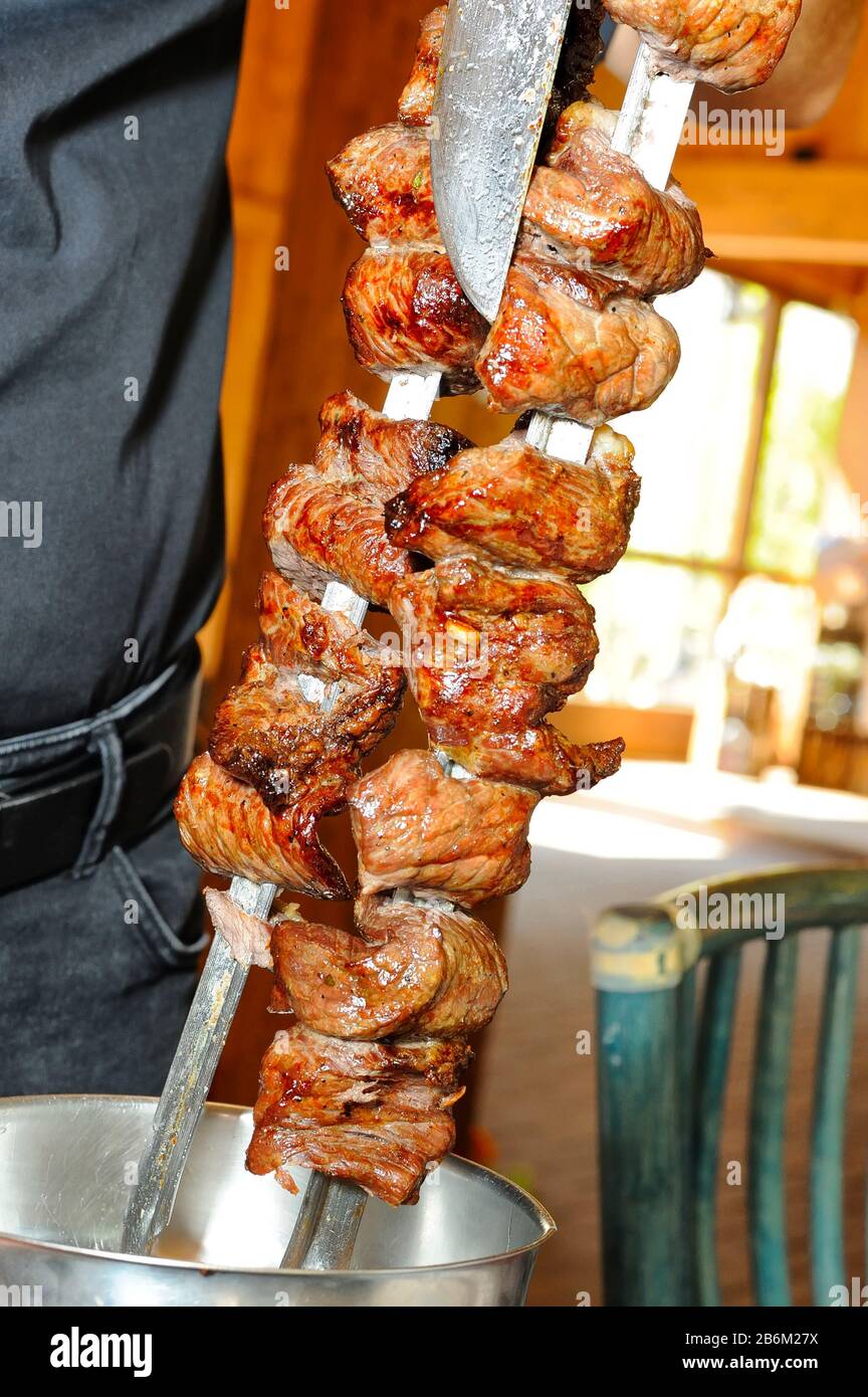 waiter hands cutting picanha, traditional Brazilian barbecue Stock