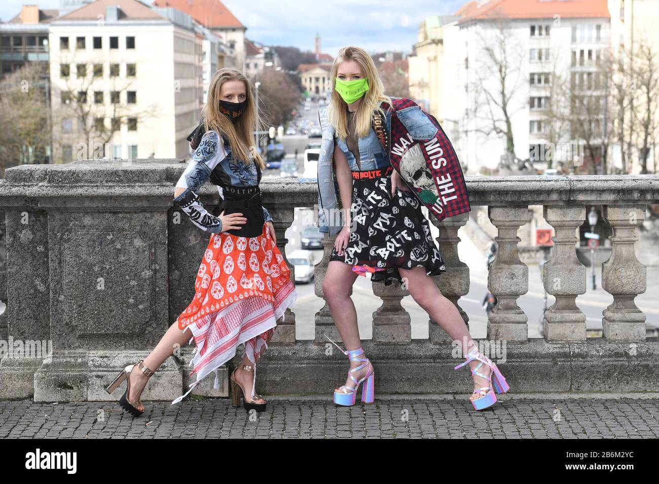 Munich, Germany. 11th Mar, 2020. dpa-exclusive: The models Verena Schmidl (l) and Klarika Koly present themselves with the colourful, glittering and shrill fashion of fashion designer Pia Bolte at the Friedensengel with colourful mouthguards. The mouthguard is not only meant to protect against viruses, but also to underline the extravagance of Bolte's fashion line. Credit: Felix Hörhager/dpa/Alamy Live News Stock Photo