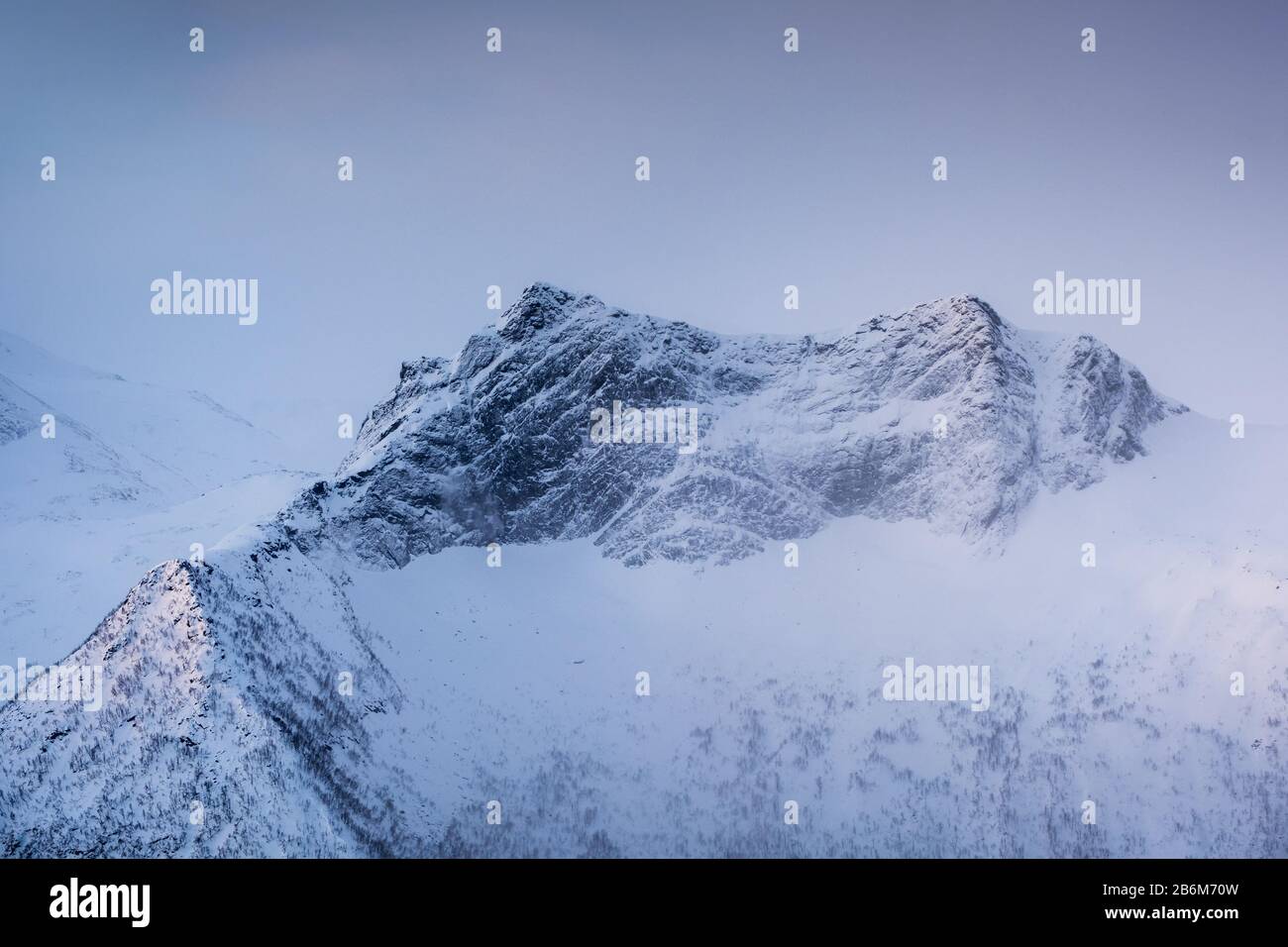 Snowy mountain peak with light in foggy at morning Stock Photo