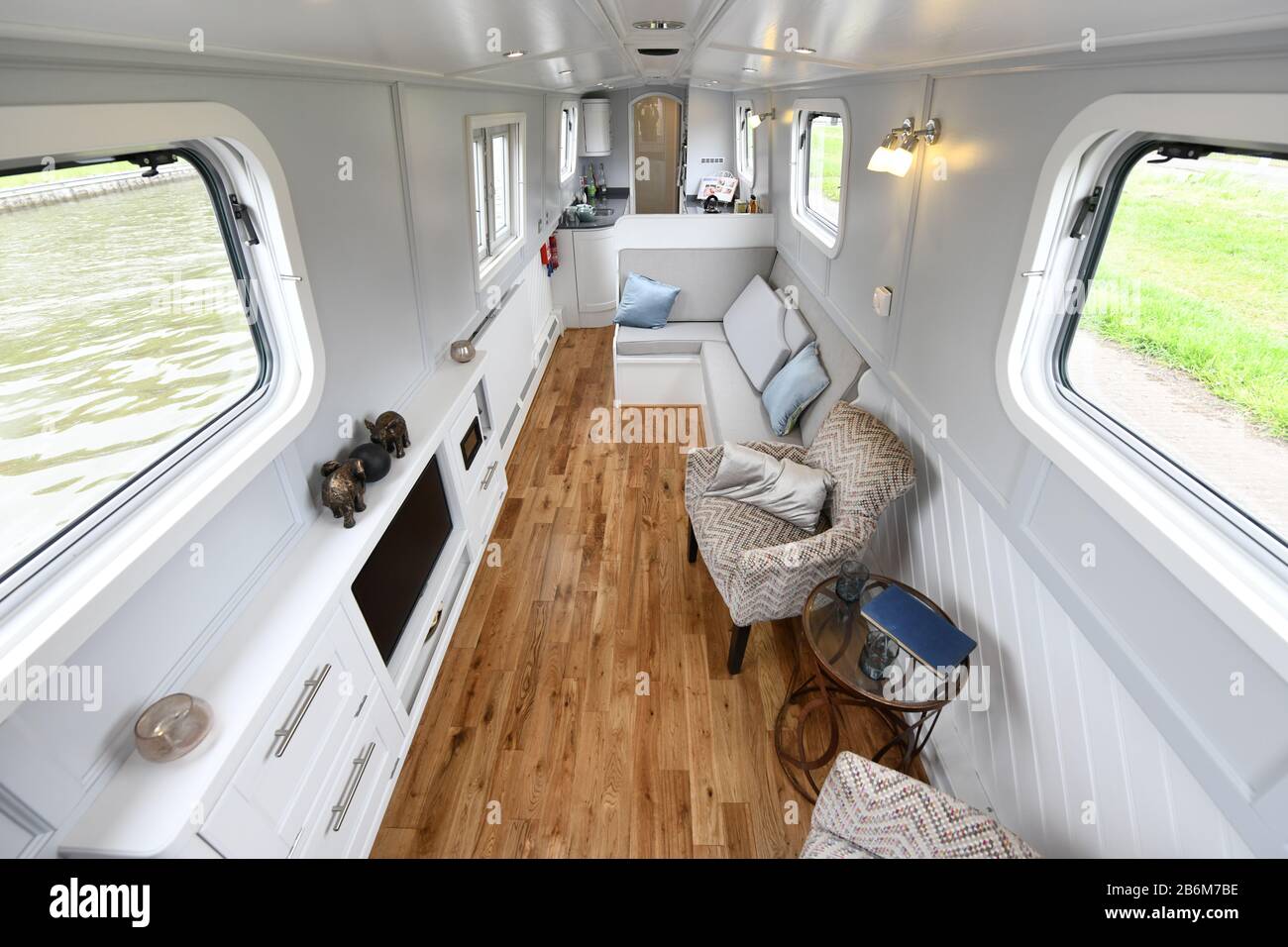 Looking into the main living area of a predominantly white coloured interior of a stylish new narrowboat on a canal. Stock Photo