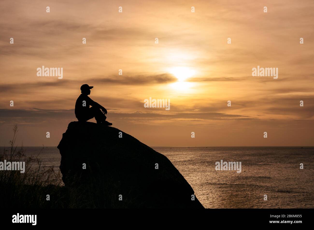 Silhouette man sitting on big rock with sightseeing of sunset in ...