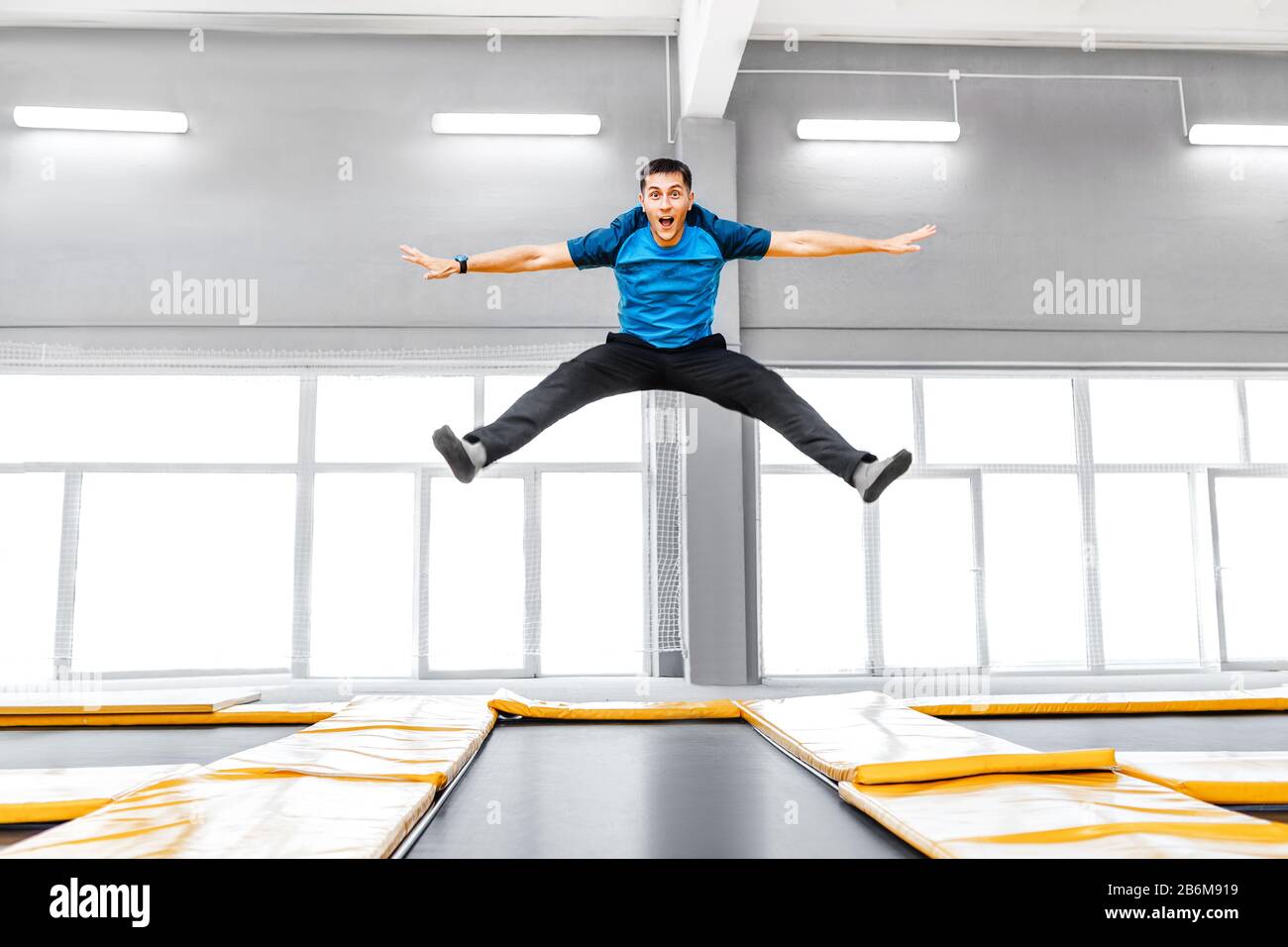 A young fit happy man jumping and flying on trampoline in fitness gym ...