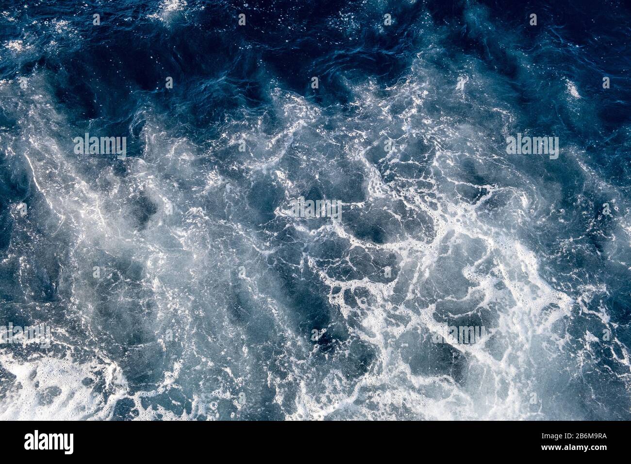Top down aerial view of sea water surface. White foam waves texture as