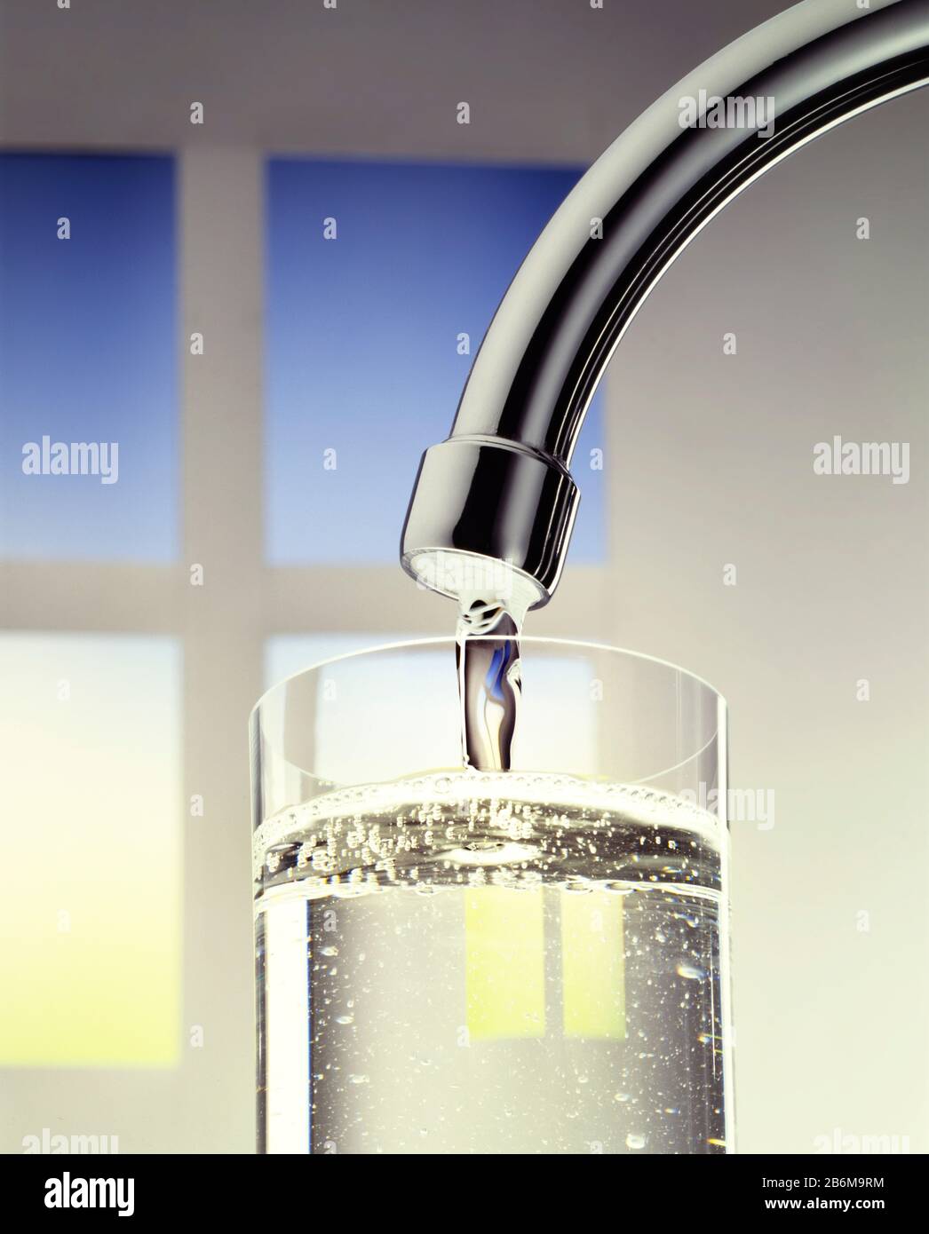 A kitchen tap delivers clear water to a drinking glass. Stock Photo