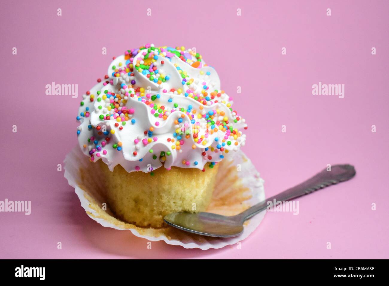 Cupcake con Chispas de Colores en fondo rosa Stock Photo