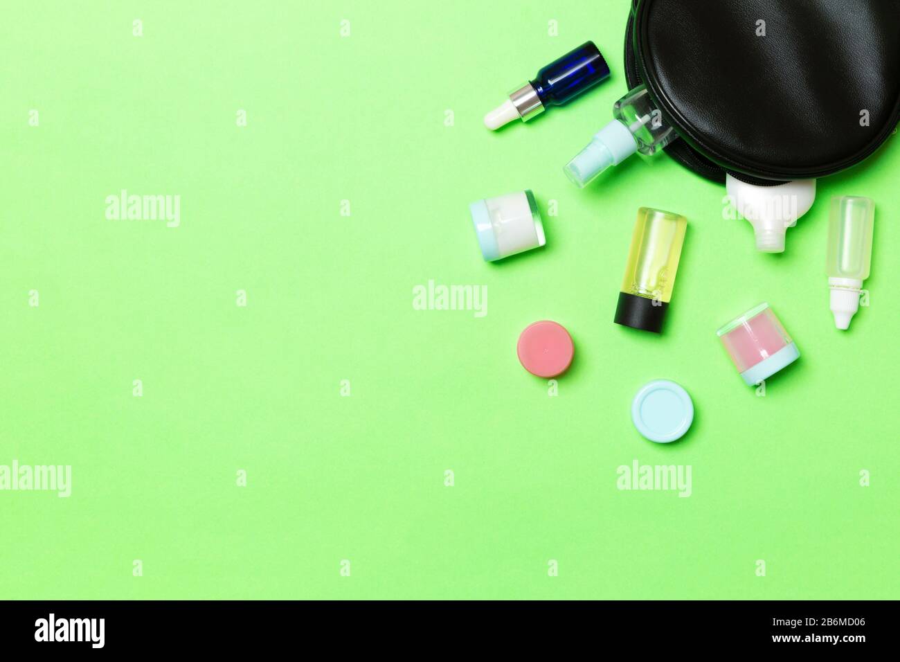 Group of beauty cream bottles dropped out of the cosmetics bag on green ...