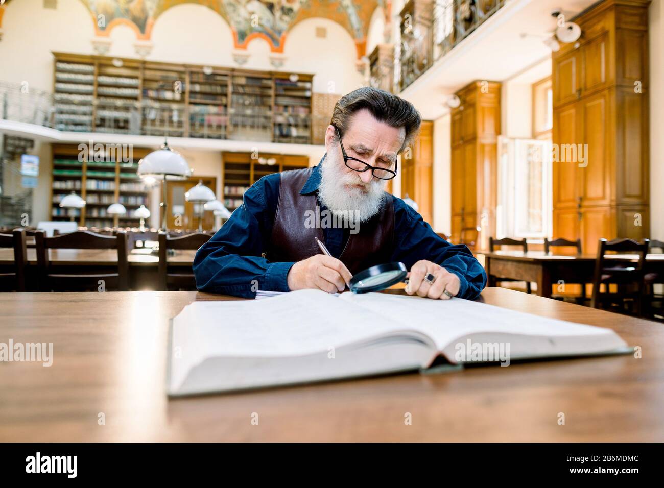Stylish Old Senior Elderly Man With White Beard And Glasses Working In An Antique Library With Books Sitting At The Vintage Table Education Library Stock Photo Alamy