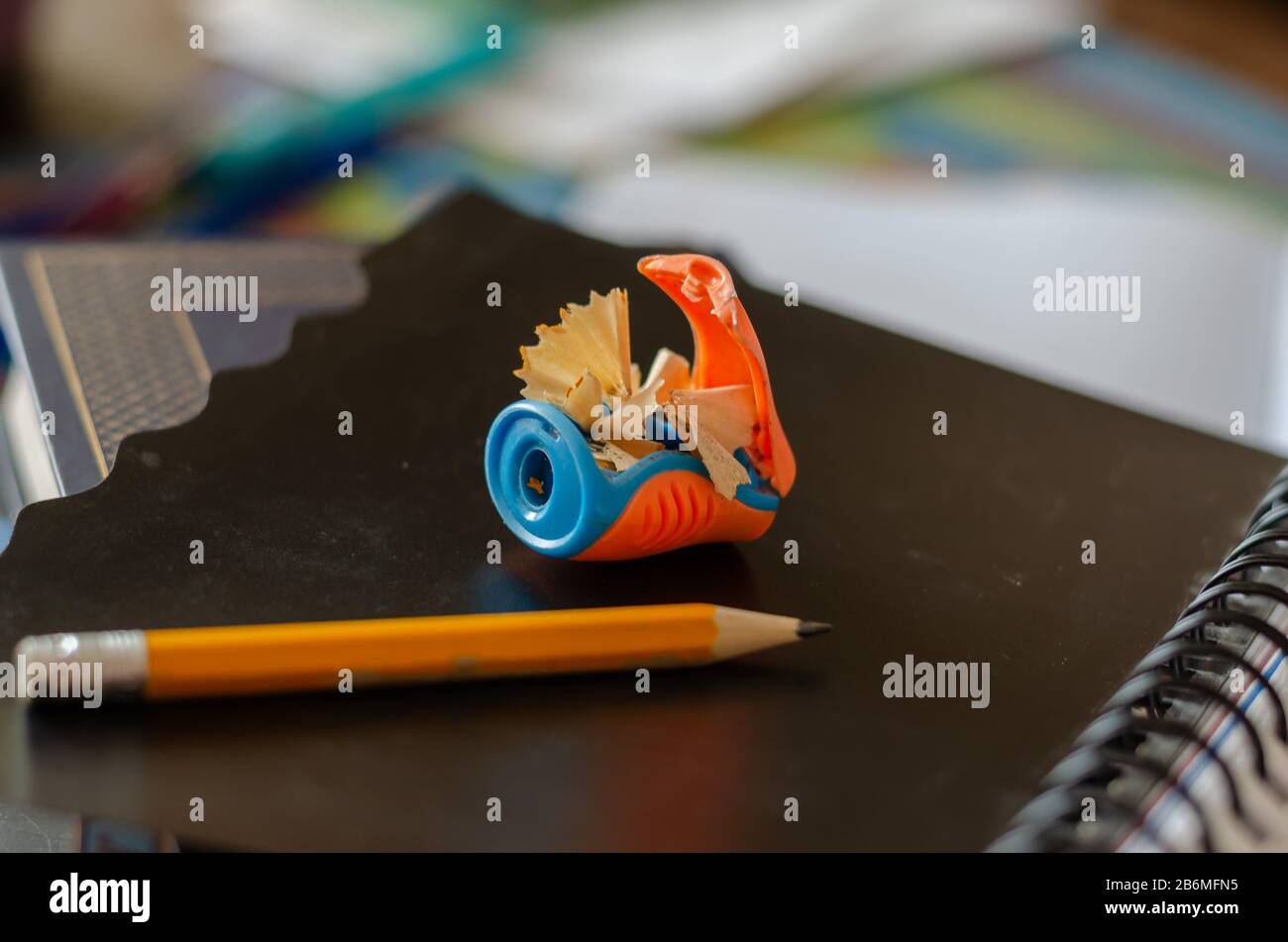Pencil sharpener with pencil. Sharpened wooden pencil on a black notebook. The concept of training, education. Side view. Selective focus. Close-up. Stock Photo