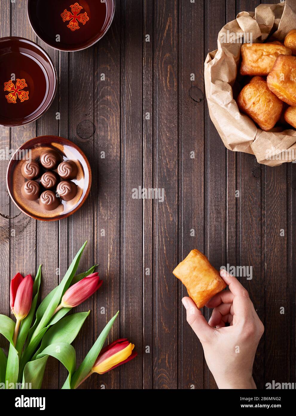 Kazakh national food and tulips during Nauryz festival on wooden brown background top view. Stock Photo