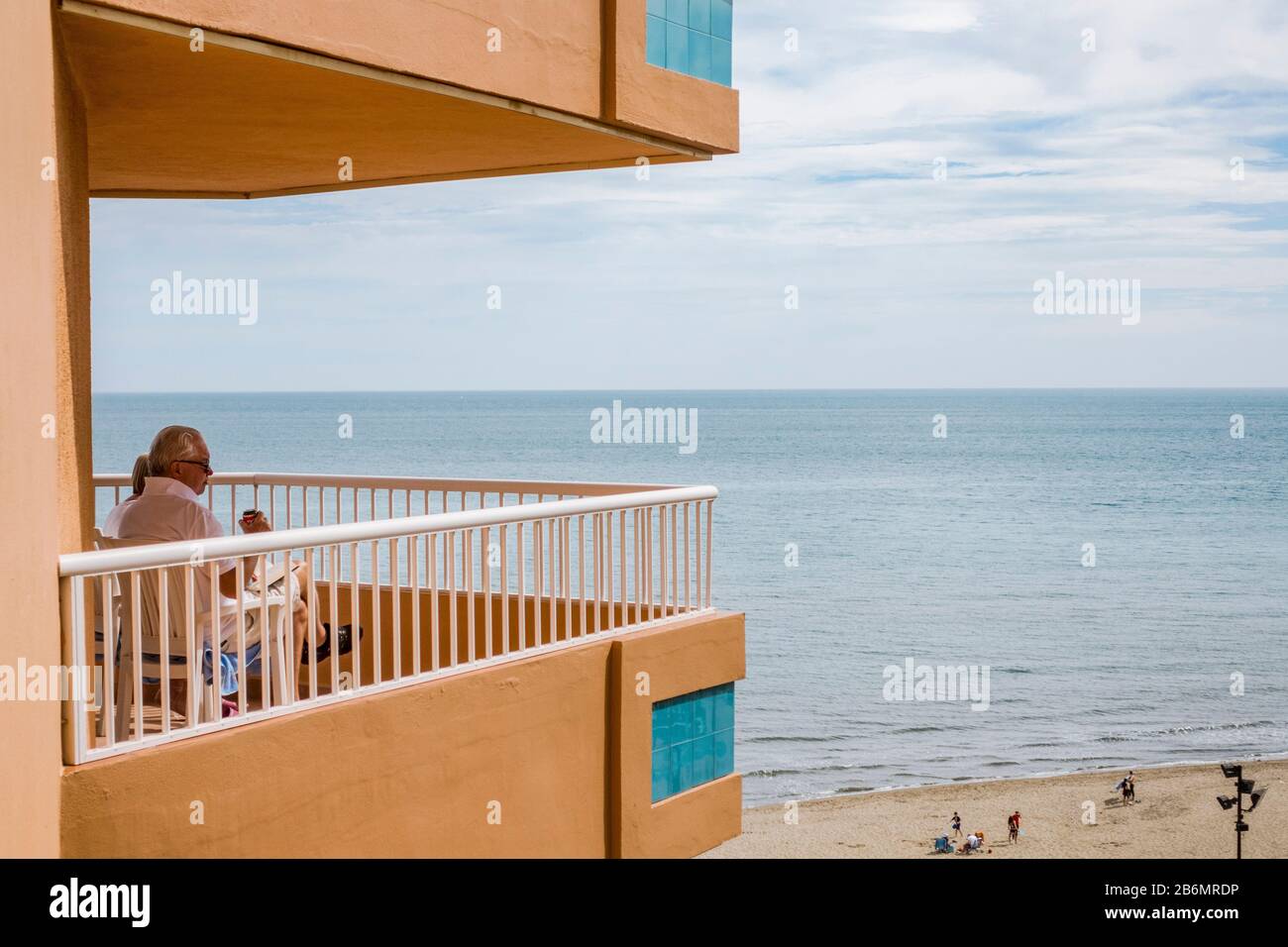 Man on balcony Apartment block, viewing beach of Fuengirola, Andalusia, Spain. Stock Photo