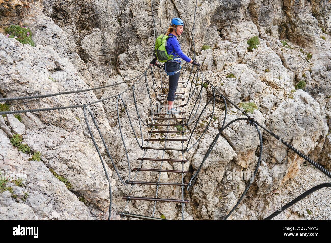 Woman on a via ferrata suspended wire bridge at Cesare Piazzetta klettersteig route, Sella group, Dolomites mountains, Italy. Stock Photo