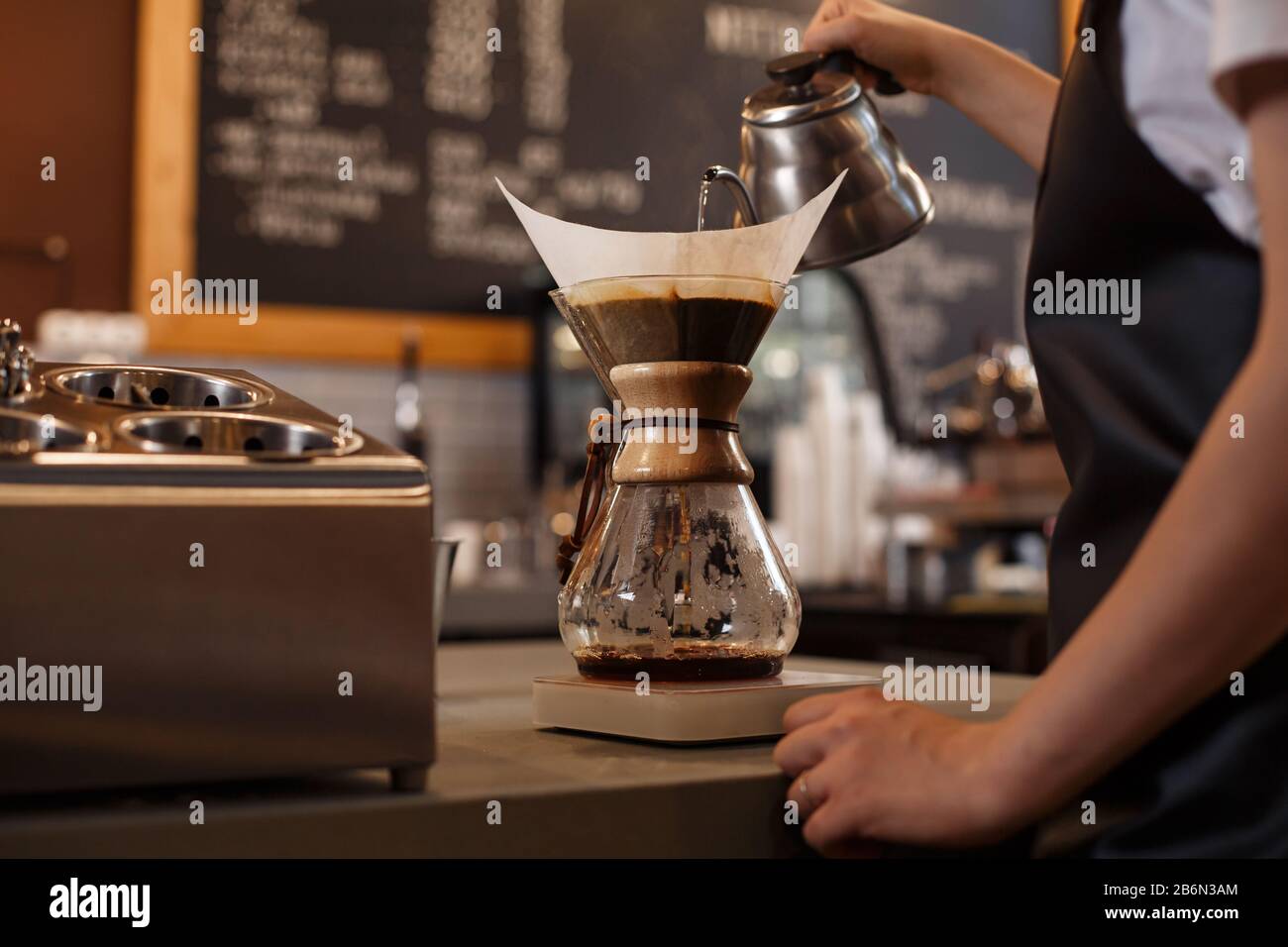 Professional barista preparing coffee using chemex pour over coffee