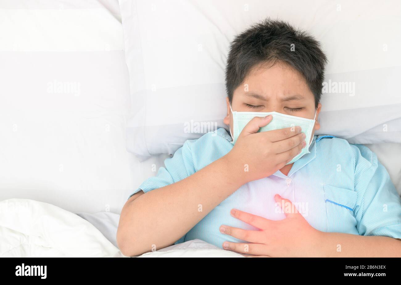 Asian fat boy wear hygienic mask is coughing and chest pain (red spot