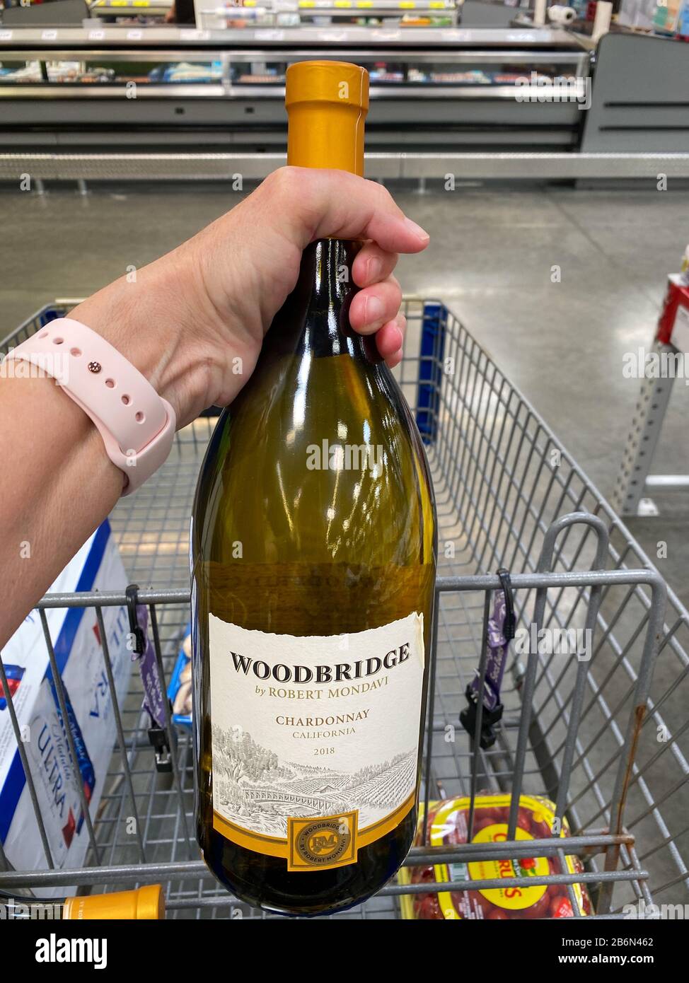Orlando,FL/USA-3/2/20: A hand putting  a bottle of Woodbridge Robert Mondavi Chardonnay wine in a cart at a Sams Club in Orlando, Florida. Stock Photo