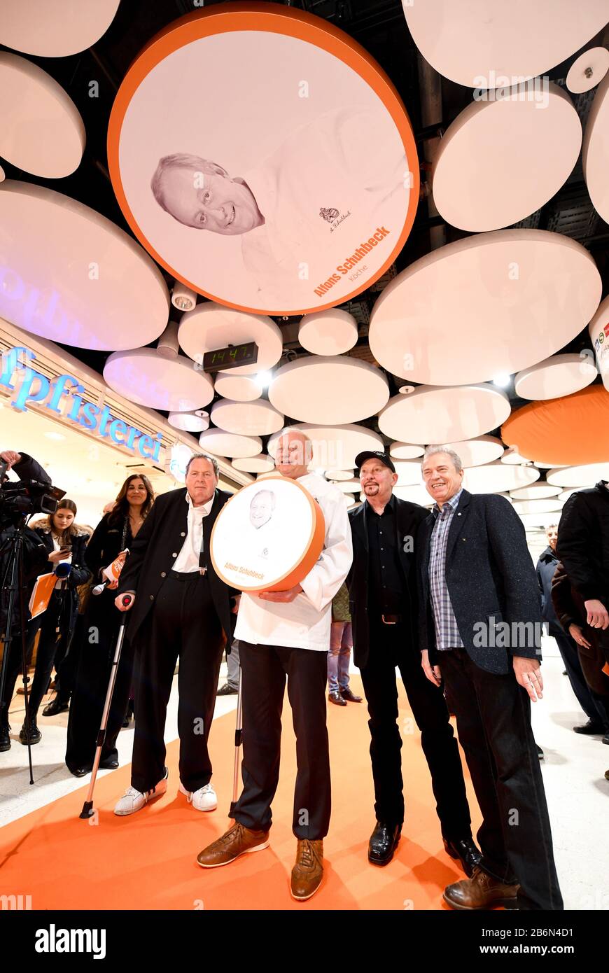 Munich, Germany. 11th Mar, 2020. Karen Webb (l-r), presenter, Ottfried Fischer, actor, Alfons Schuhbeck, star chef, Barny Murphy and Günther Sigl, musician of the band Spider Murphy Gang, stand in the Stachus Passages under a ceiling circle in the Sky of Fame with a photo of Schubeck. In the Sky of Fame, on the ceiling circles of the Stachus Passages, there are pictures of Munich personalities. Fischer, Schubeck, Murphy and Sigl unveiled their pictures on 11.03.2020. Credit: Tobias Hase/dpa/Alamy Live News Stock Photo