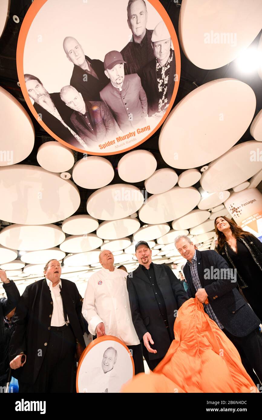 Munich, Germany. 11th Mar, 2020. Ottfried Fischer (l-r), actor, Alfons Schuhbeck, star cook, Barny Murphy as well as Günther Sigl, musician of the band Spider Murphy Gang, and Karen Webb, presenter, are standing in the Stachus Passages under a ceiling circle in the Sky of Fame with a photo of the band Spider Murphy Gang. In the Sky of Fame, on the ceiling circles of the Stachus Passages, there are pictures of Munich personalities. Fischer, Schubeck, Murphy and Sigl have revealed their pictures. Credit: Tobias Hase/dpa/Alamy Live News Stock Photo