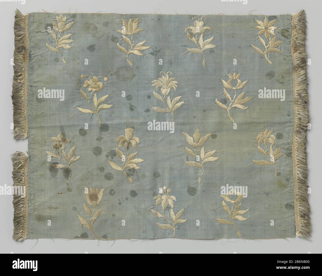 Fragment zijdeweefsel met borduurwerk Fragment blauw zijdeweefsel met wit  borduurwerk. Het patroon heeft rijen verspringende bloemtakken. Het  fragment heeft aan twee zijden witte, zijde franje. Manufacturer : Plaats  manufacture: Nederland Dating: ca., image size:1300x1114