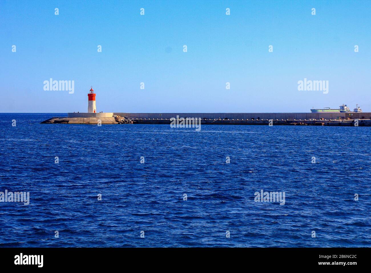 small white and red lighthouse over the blue sea Stock Photo
